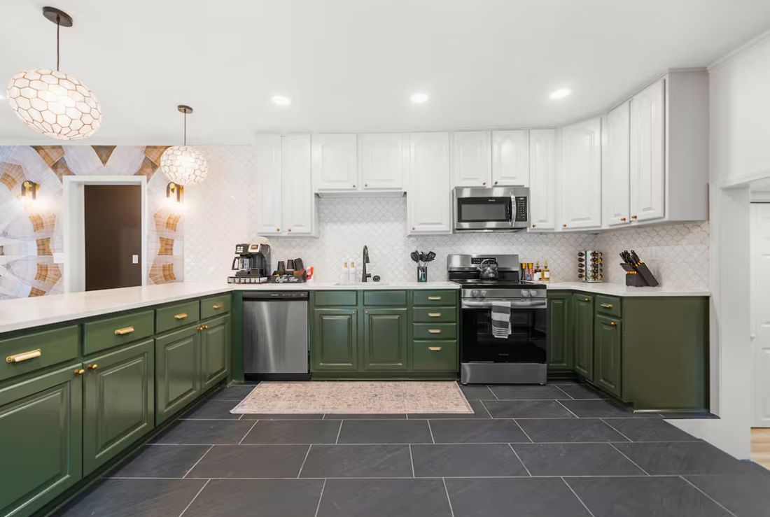 Kitchen remodel with forest green lower cabinets, white upper cabinets, an arabesque tile backsplash, brass hardware and slate tile flooring.